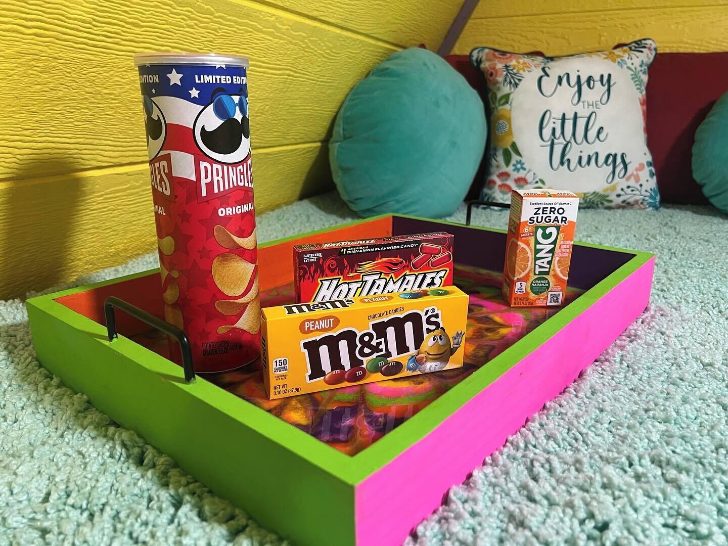 Una bandeja con bocadillos que incluyen Pringles, Hot Tamales y M&M's.