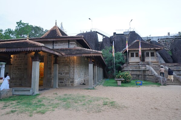 A stone building with a tiled roof, a staircase, and a flagpole.