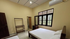 Habitación de hotel con cama, armario, espejo y ventana con celosía decorativa.
