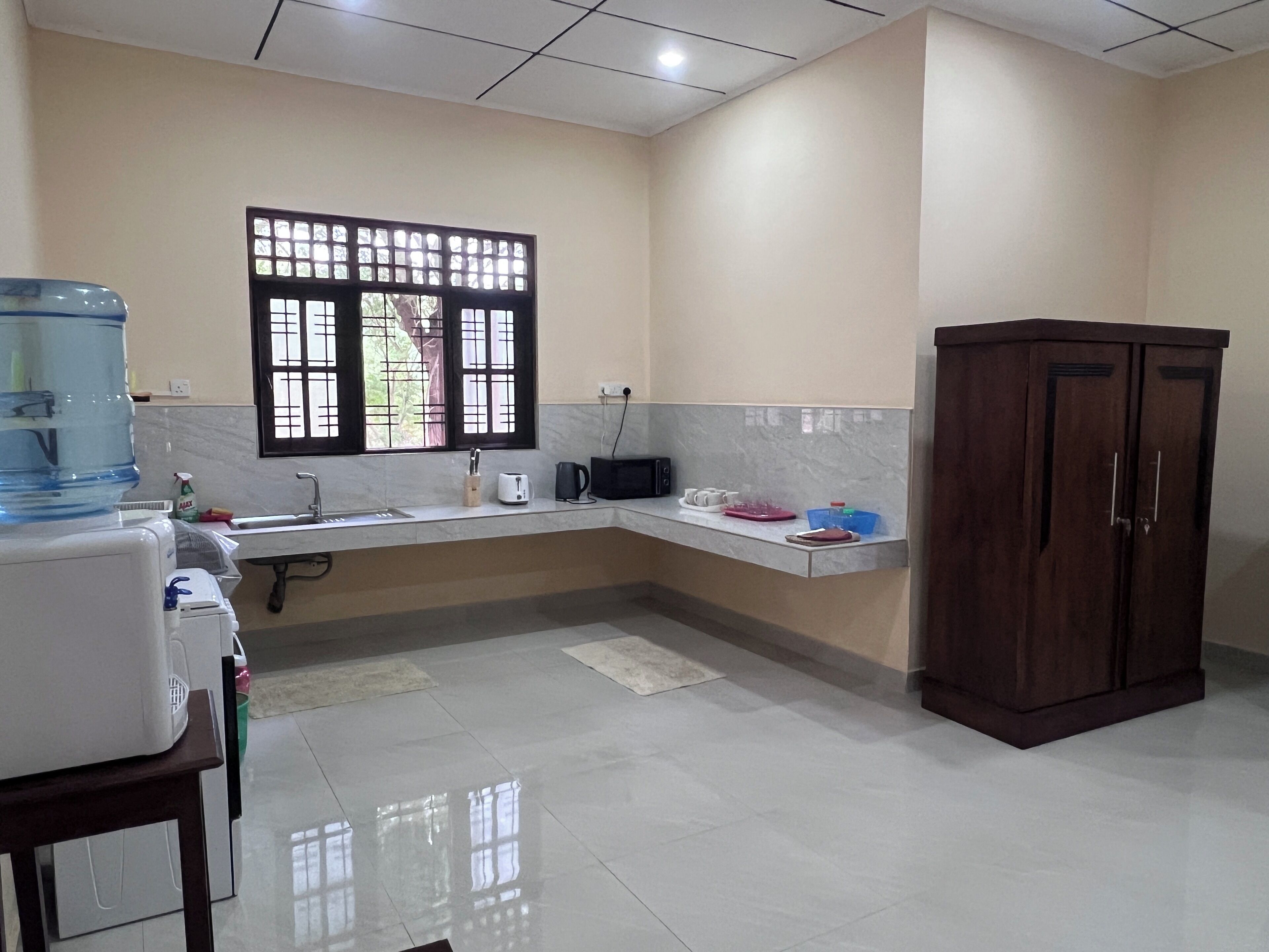 A kitchen with a water dispenser, a microwave, a sink, and a cabinet.