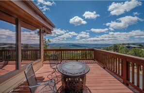 A wooden deck with a glass door, a round table, and a chair.