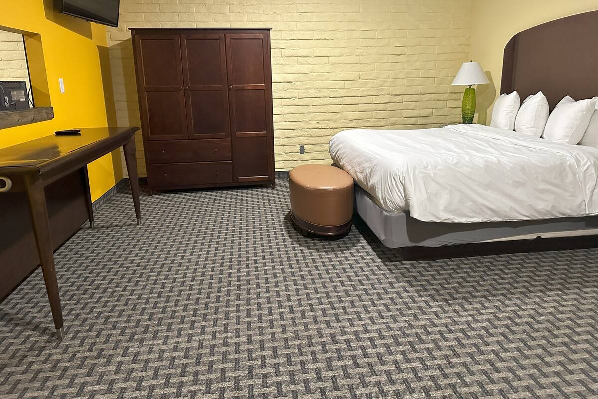 A hotel room with a bed, a desk, a chair, a wardrobe, and a television on the wall.