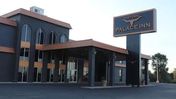 Experience the grand entrance of the Historic Palace Inn, featuring a covered area supported by columns and large windows.