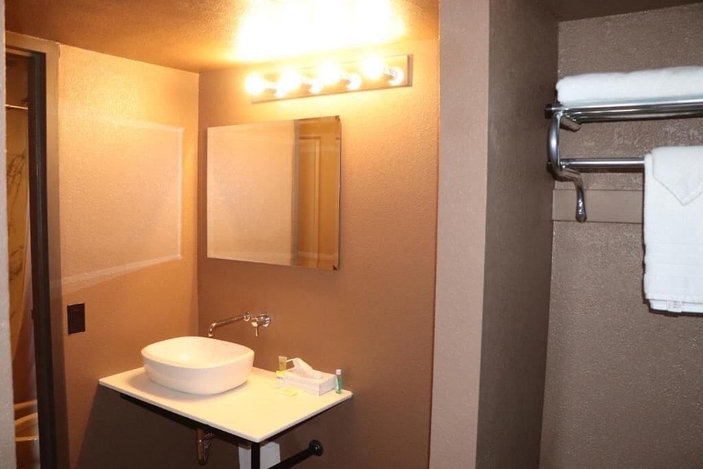 Une salle de bain avec un lavabo blanc, un miroir et un porte-serviettes.