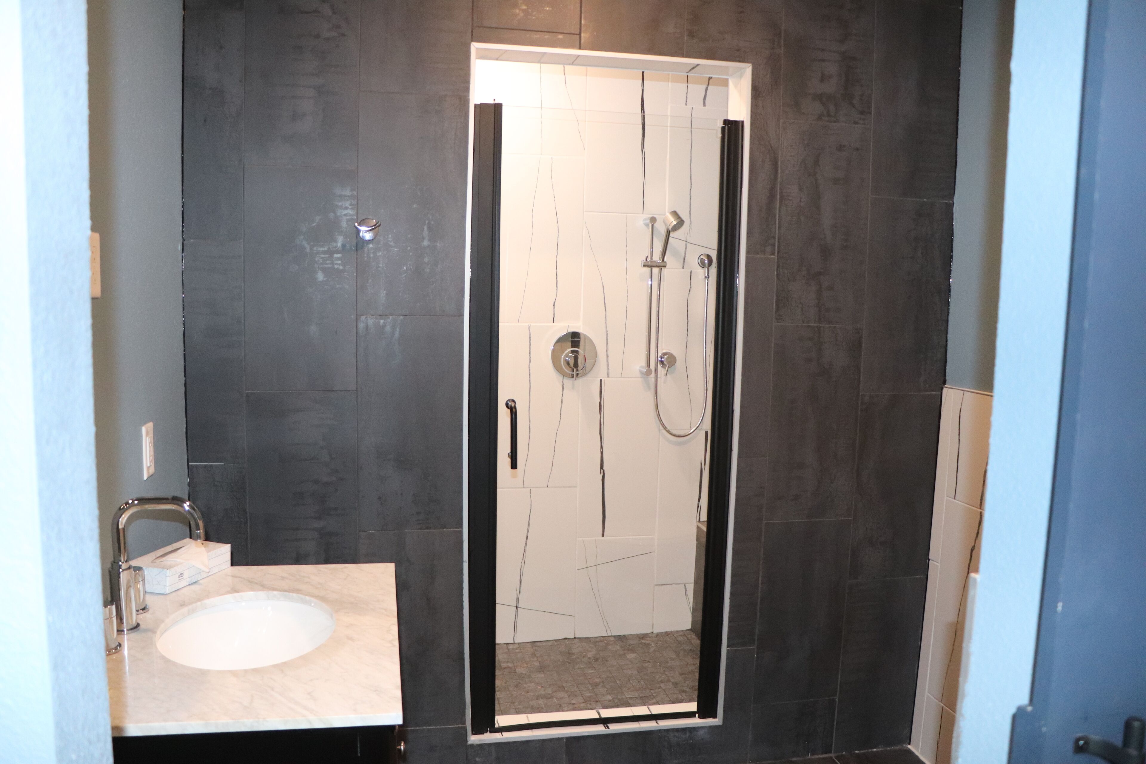 A modern bathroom with a large mirror, a sink, and a shower enclosure.