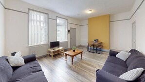 A living room with a sofa, a coffee table, a TV, and a small table with a plant. - City Centre-University Home from Home (Sunderland)