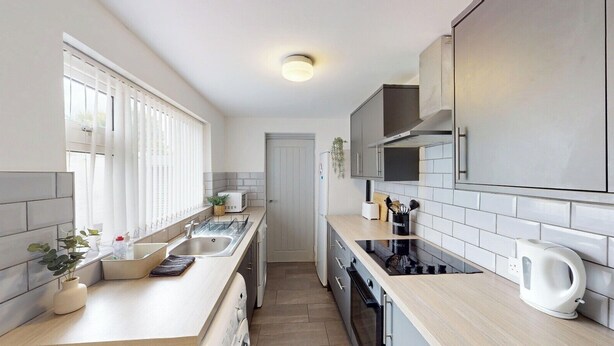 A modern kitchen with a light wood countertop, stainless steel appliances, and white tiled backsplash. - City Centre-University Home from Home (Sunderland)
