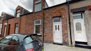 Une rangée de maisons mitoyennes avec une voiture garée devant.