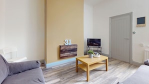 Un salon moderne avec un canapé, une table basse, un téléviseur et une porte.