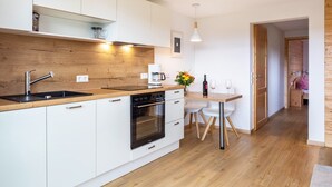 A modern kitchen with white cabinets, a wooden countertop, a built-in oven, and a dining area with a table and chairs. - Apartment 'Gästehaus Steiert Fewo Kuhbergblick' with Mountain View, Shared Garden and Wi-Fi (Lenzkirch)
