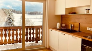 A kitchen with a wooden countertop, a sink, and a view of a snowy landscape through a sliding glass door. - Apartment 'Gästehaus Steiert Fewo Kuhbergblick' with Mountain View, Shared Garden and Wi-Fi (Lenzkirch)