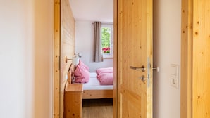 A wooden door leading to a room with a bed, a small table, and a window with curtains. - Apartment 'Gästehaus Steiert Fewo Kuhbergblick' with Mountain View, Shared Garden and Wi-Fi (Lenzkirch)