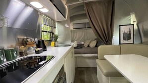 Une cuisine compacte pour camping-car, équipée d’un évier, d’une cuisinière et de placards de rangement.