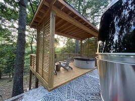 Una terraza de madera con un jacuzzi, una parrilla y un tapete estampado.