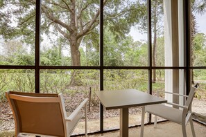 Enjoy a peaceful view of the lush landscape from the large window, perfect for dining or relaxing in this modern room.