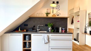 Una cucina moderna con forno integrato, lavello e piano di lavoro con diversi elettrodomestici e una pianta.