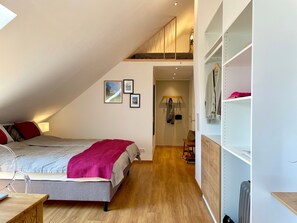 Ein Schlafzimmer mit einem Bett, einem Schreibtisch, einem Stuhl, einem Kleiderhaken und einer Heizung.