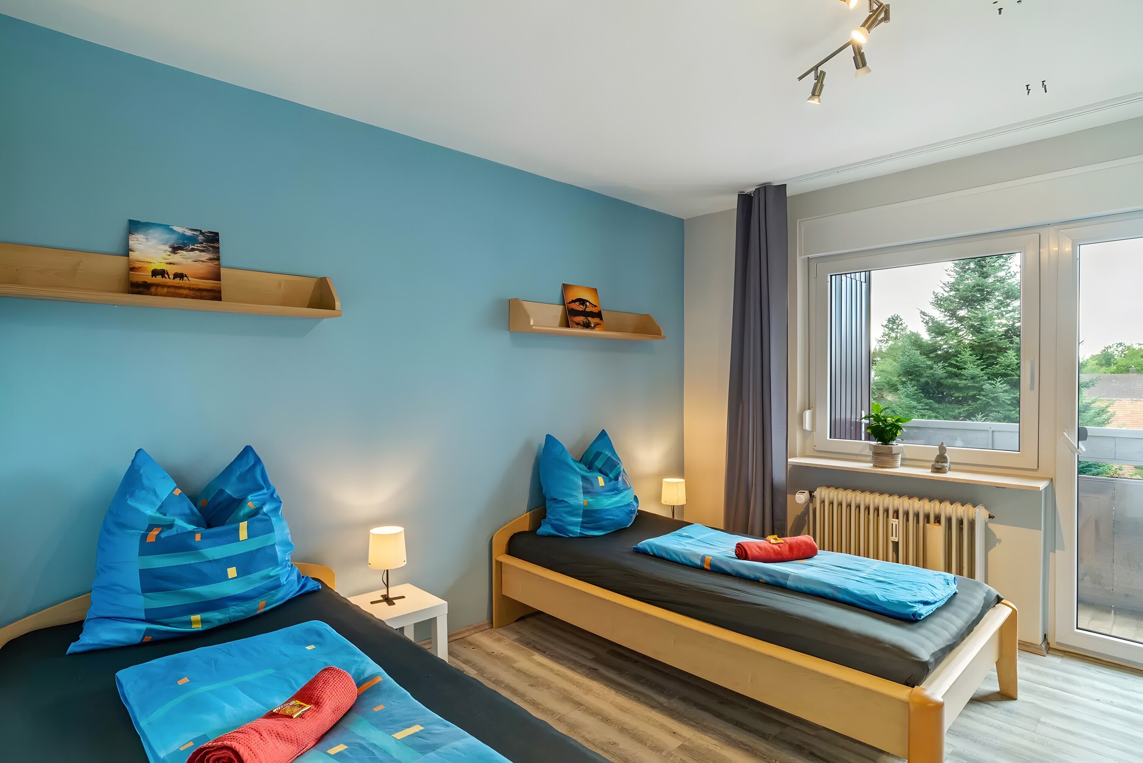A bedroom with two beds, a window with a view, and a radiator.