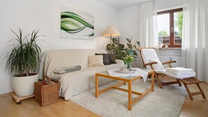 Een woonkamer met een bank, een salontafel, een stoel, een potplant en een lamp.