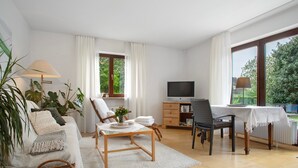Een moderne woonkamer met een bank, een salontafel, een televisie en een eethoek met een tafel en stoelen.