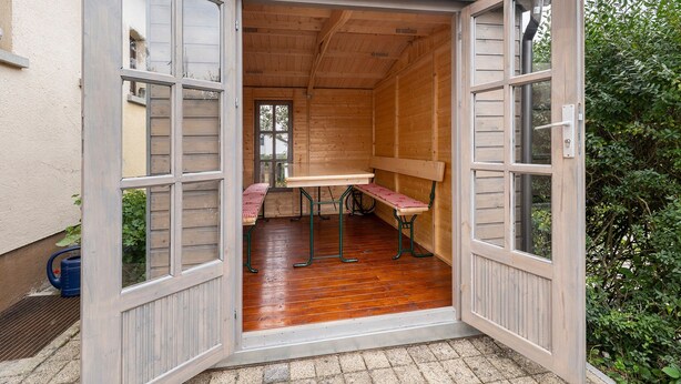 Une structure en bois ouverte, comprenant une table, des bancs, une fenêtre et une porte.