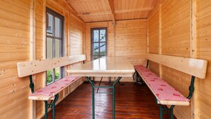 L’intérieur d’une cabane en bois, avec une longue table et des bancs, une fenêtre et une porte.