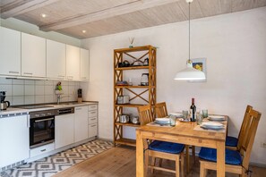 A kitchen with white cabinets, a wooden dining table with blue chairs, and a hanging pendant light.