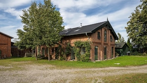 A brick house with a sloped roof, surrounded by a gravel driveway and a grassy lawn.