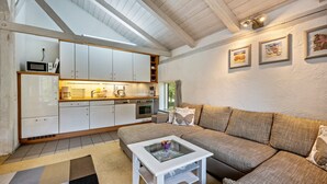 Una cocina moderna con armarios blancos y una zona de comedor con sofá y mesa de centro.