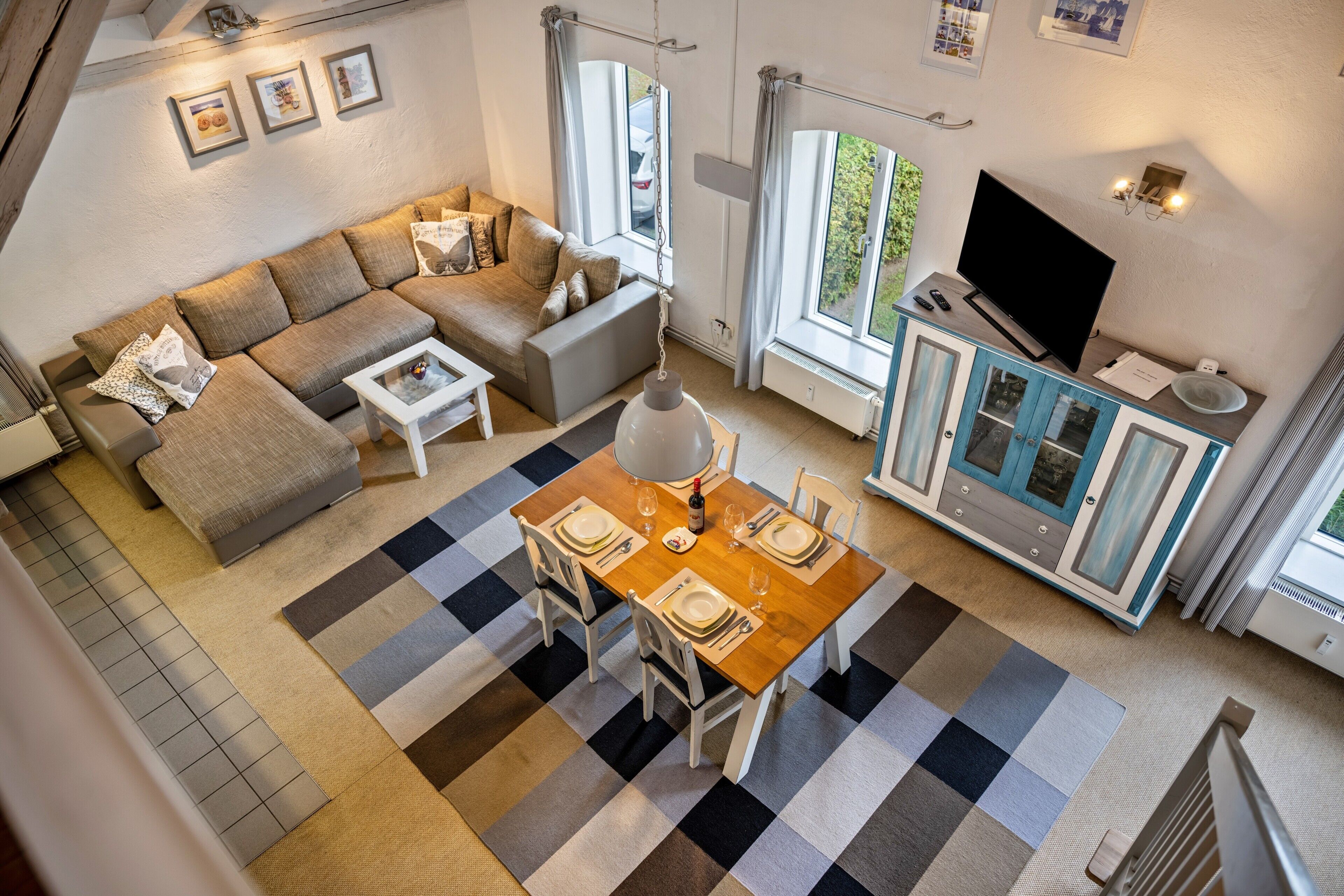 En moderne stue med sofa, spisebord til fire personer og fjernsyn.