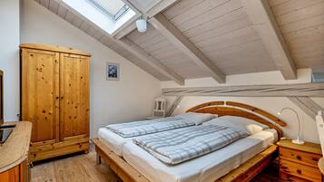 A bedroom with a wooden bed, a wooden wardrobe, a skylight, and a wooden ceiling.