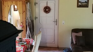 A living room with a dining table, wicker chairs, a sofa, a door with a wreath, and a framed picture on the wall. - Holiday Home 'Jagdhaus Franz' with Terrace (Kloster Lehnin)