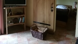 A room with a television on a wooden stand, a bed with a white duvet, a wall-mounted deer skull, and a sliding barn-style door. - Holiday Home 'Jagdhaus Franz' with Terrace (Kloster Lehnin)