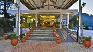 A hotel entrance with a covered walkway, steps, and potted plants. - Hillcrest Resort by DLS Hotels (Shimla)
