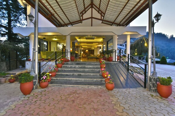 A hotel entrance with a covered walkway, steps, and potted plants. - Hillcrest Resort by DLS Hotels (Shimla)