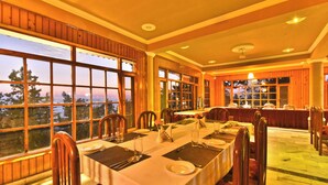 A dining area with large windows, wooden paneling, and a view of the outdoors. - Hillcrest Resort by DLS Hotels (Shimla)