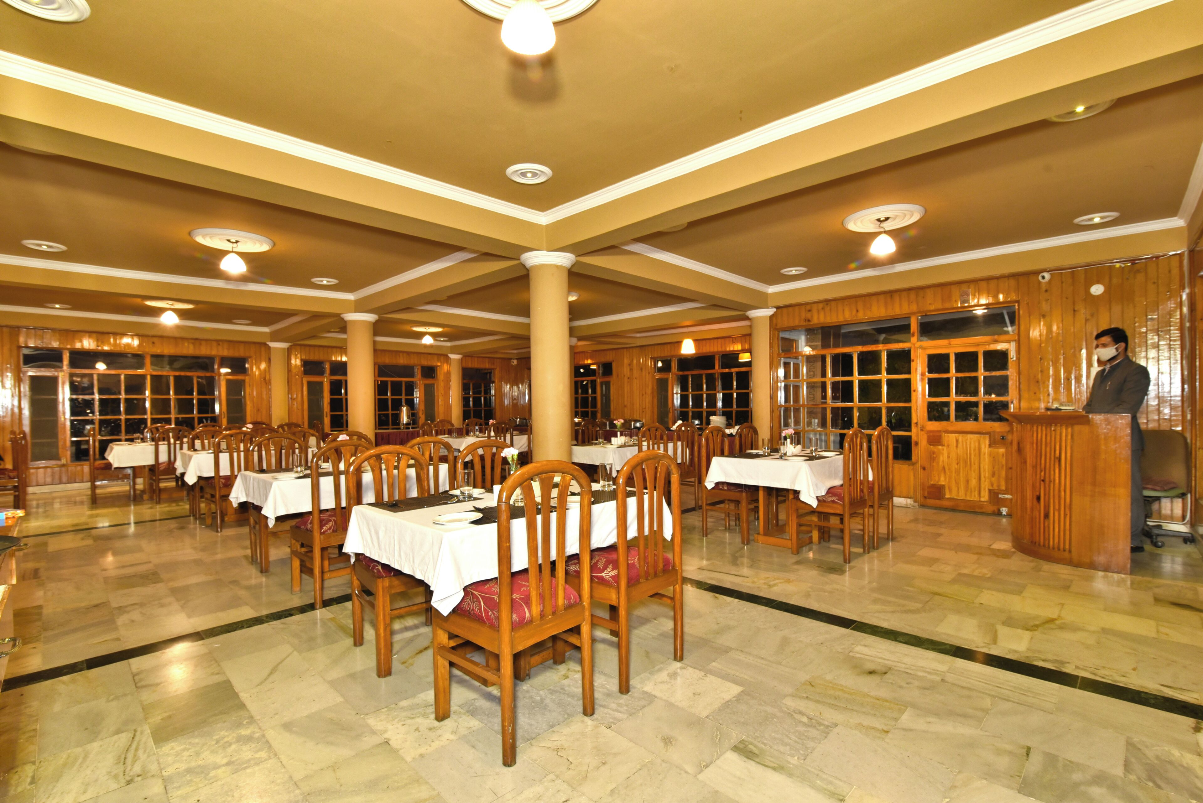 A spacious dining area with multiple tables and chairs, wooden paneling, and a podium.