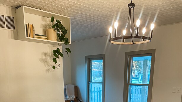 A living room with a brown leather sofa, a wooden coffee table with decorative items, a potted plant, and a chandelier. - Freshly Updated house near Wilson Lake, Kansas’s nicest lake!!! (Lucas)