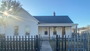 A single-story house with a front porch, a chimney, and a gated driveway. - Freshly Updated house near Wilson Lake, Kansas’s nicest lake!!! (Lucas)
