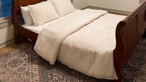 A bedroom with a wooden bed, two windows, a patterned rug, and two framed pictures on the wall. - Freshly Updated house near Wilson Lake, Kansas’s nicest lake!!! (Lucas)