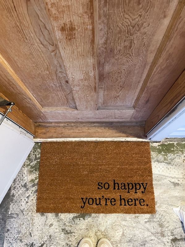 A wooden ceiling with a brown doormat that reads "so happy you're here."