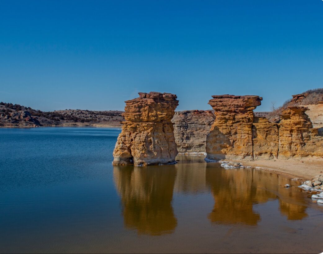 A natural landscape with rock formations and a calm body of water.
