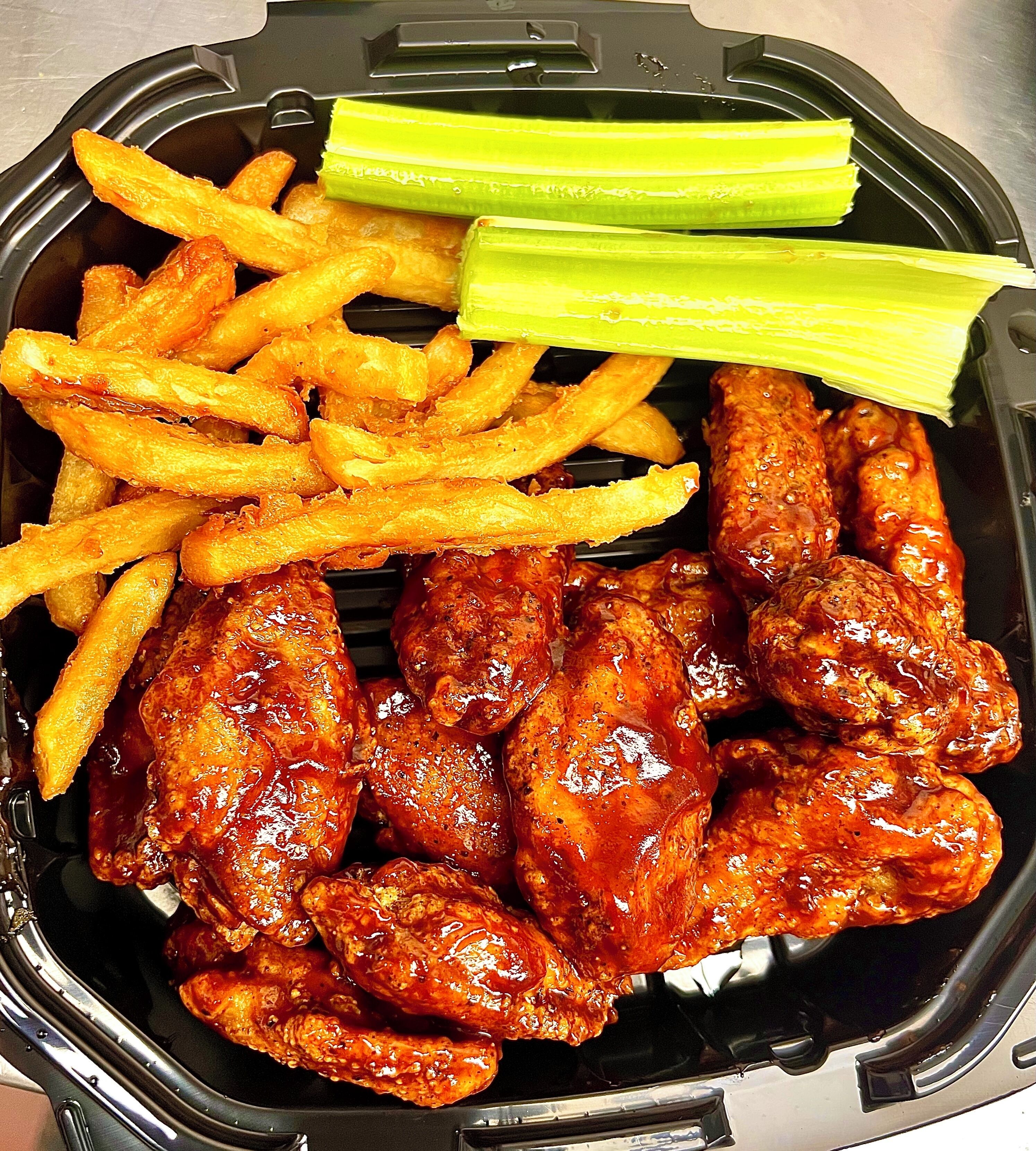 A food container with wings, fries, and celery.