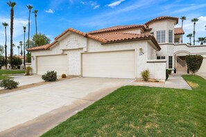 A two-story house with a garage, a covered driveway, and a well-maintained lawn. - Beautiful Desert Falls Country Club Upper Unit Condo (Palm Desert)