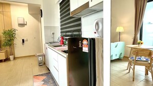 Een moderne keuken met een koelkast, fornuis en spoelbak. Er is een eethoek met een tafel en stoelen.