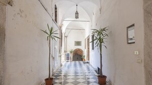 A hallway with checkered flooring, potted plants, and a central door with a sign. - Sky Room Carrara hydromassage with parking (Carrara)