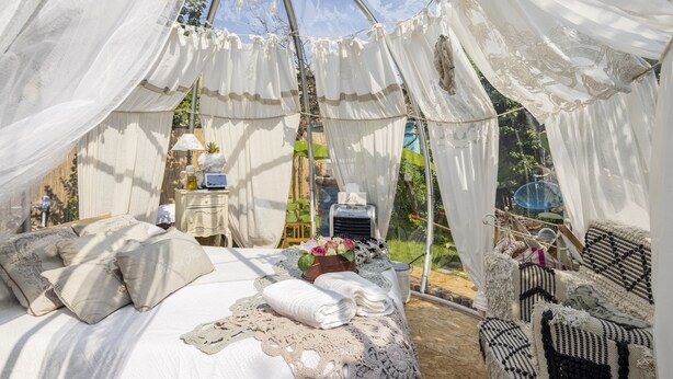 A tented room with a bed, pillows, a table with a lamp, and a chair. - Sky Room Carrara hydromassage with parking (Carrara)