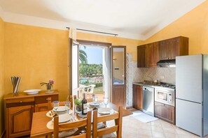 Une cuisine avec des meubles en bois, un réfrigérateur, une cuisinière et un coin repas avec une table mise pour deux personnes.