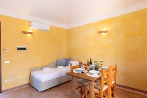Une pièce de taille modeste comprenant un lit, une table à manger avec des chaises et un climatiseur fixé au mur.
