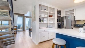 A modern kitchen with white cabinetry, a blue island, and a view to the outside.